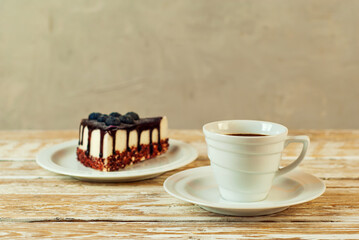 Coffee in a white ceramic mug. Cake with coffee for breakfast. Coffee on an old wooden table.