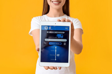 Young woman holding tablet computer with delivery service application on screen against color...