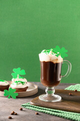 Irish coffee in green cup and special cupcakes for St Patricks Day on green background. Happy st...