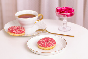 Fototapeta na wymiar Cup of tea, sweet strawberry donut on golden plate with hydrangea flower
