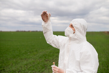 Young man in a protective suit controls the chemicals in the fields.