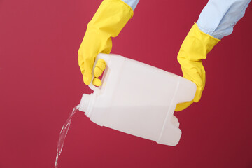 Man pouring out liquid from plastic canister on color background