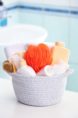 Basket with cosmetic products and bath accessories on table