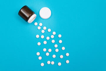 Global Pharmaceutical Industry and Medicinal Products - White Pills or Tablets Scattered from the Bottle, Lying on Blue Background, Top View, Flat Lay