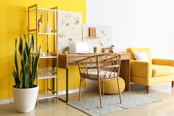 Stylish workplace with peg board on yellow and white wall background