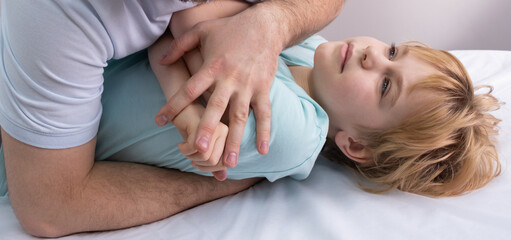 Obraz na płótnie Canvas An osteopath works with the child. Work with the chest, shoulders and spine. There is a teenage child on the couch. The doctor puts pressure on the patient's chest. Posture correction