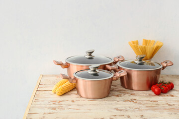 Copper cooking pots and raw food on wooden table against white background