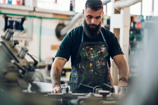 Male worker using a printing machine in a workshop
