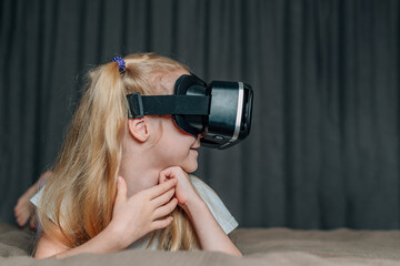 child girl at home in virtual reality VR glasses watching video, playing games. modern children are well versed in technological innovations. generation alpha