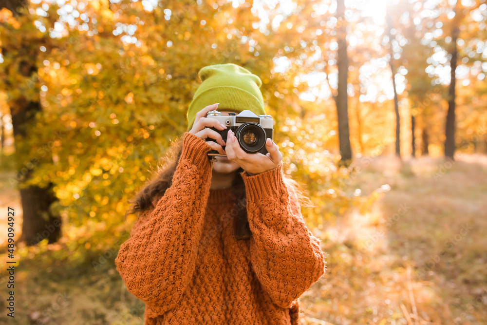 Wall mural Young woman taking picture in autumn forest