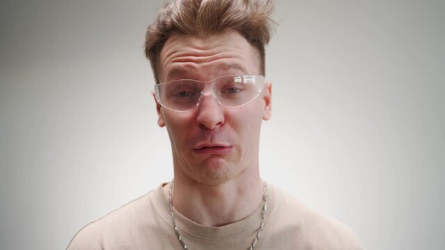 Portrait of a funny man freak in glasses grimaces at the camera on a white background 