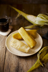 Humitas are savory steamed fresh corn cakes, a traditional Ecuadorian appetizer. It’s accompanied by coffee, on a wooden background. 