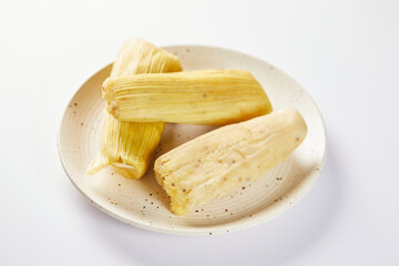 Humitas are savory steamed fresh corn cakes, a traditional Ecuadorian appetizer. On a white background. 