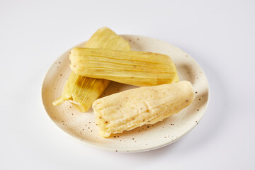 Humitas are savory steamed fresh corn cakes, a traditional Ecuadorian appetizer. On a white background. 