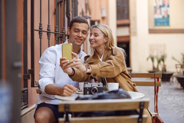 Happy couple taking selfie on smartphone while sitting in cafe