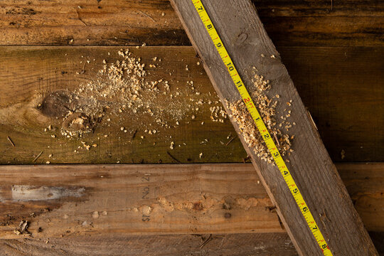 Measuring tape on top of a wooden plank.