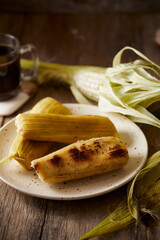 Humitas are savory steamed fresh corn cakes, a traditional Ecuadorian appetizer. It’s accompanied by coffee, on a wooden background. 