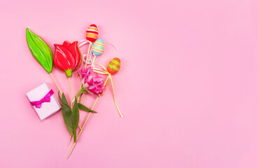 Spring greeting card concept. A bouquet of tulips, cookies in the form of a tulip, Easter eggs and a small box with a spice lies on a pink background. Easter composition copy space