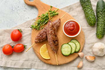 Wooden board of skewers with tasty lula kebab and vegetables on table