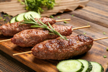 Board of skewers with tasty lula kebab on wooden background, closeup