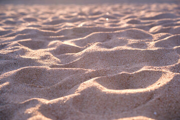 Close up of clean yellow sand surface covering seaside beach illuminated with evening light. Travel and vacations concept