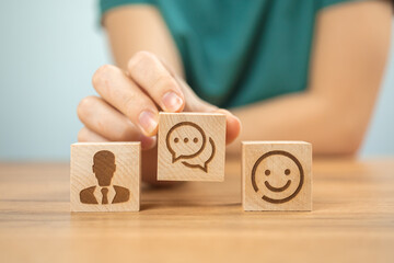 Customer center service concept background. Assist and support, cooperation. Wooden cubes with smile icons and young woman hand in office