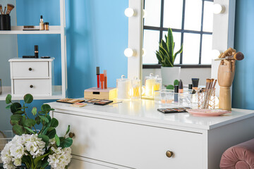 Stylish workplace of makeup artist with decorative cosmetics near blue wall