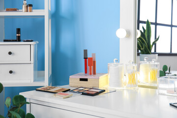 Stylish workplace of makeup artist with decorative cosmetics near blue wall