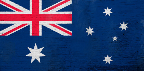 Full frame photo of a weathered flag of Australia painted on a plastered brick wall.