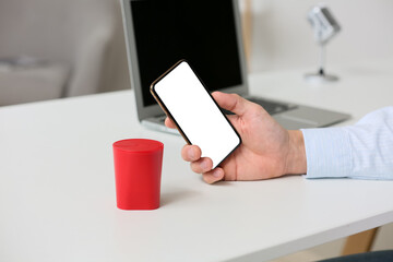 Man using mobile phone on table with wireless portable speaker, closeup