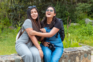 par de Mujer joven sentada sobre la naturaleza aislado con camara en la mano alegres,lentes...