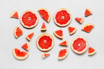 Slices of tasty ripe grapefruit on light background