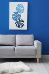 Beautiful picture and stylish sofa near blue wall