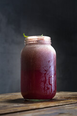 Limonada fría de frutos rojos sobre una mesa de madera con un fondo gris