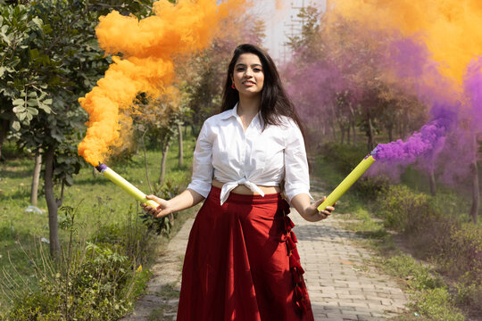 Festival of color holi, Beautiful young girl woman celebrate holi with colored multicolored smoke bombs of dry color Holi powder colour gulal abeer in the park in spring break