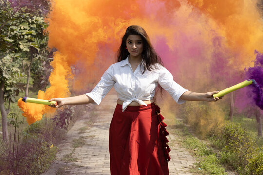 Holi festival celebration Beautiful young girl woman Multicolored smoke bombs dry color Holi powder colour gulal abeer in the park in spring break holi festival of color