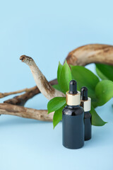 Bottles of natural cosmetic product with herbal extract on blue background