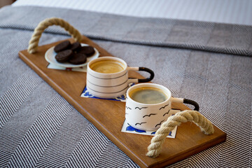 Serving cappuccino coffee on a wooden tray on a stylish table