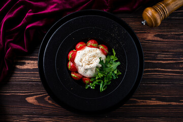 Salad with traditional italian burrata cheese with arugula and tomatoes