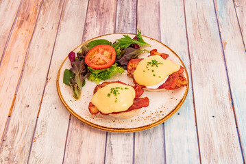 Eggs Benedict, consists of two halves of an English muffin, toast or other types of bread, usually topped with cooked ham, bacon or pastrami, poached eggs and the very popular hollandaise sauce.