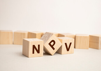Net present value. NPV the word on wooden cubes, cubes stand on a reflective surface, in the background is a business diagram. Business and finance concept