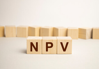 Net present value. NPV the word on wooden cubes, cubes stand on a reflective surface, in the background is a business diagram. Business and finance concept