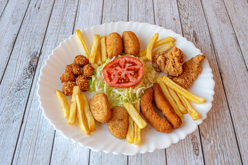 Combo of starters with croquettes, French fries, chicken fingers, chicken popcorn, battered jalapeños and tomato and lettuce salad