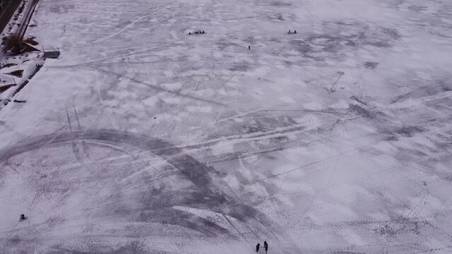 Cyclist rides on a frozen lake, people walk on ice