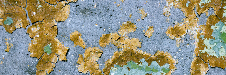Peeling paint on the wall. Panorama of a concrete wall with old cracked flaking paint. Weathered rough painted surface with patterns of cracks and peeling. Wide panoramic grunge texture for background