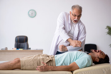 Obraz premium Young male patient visiting old male doctor