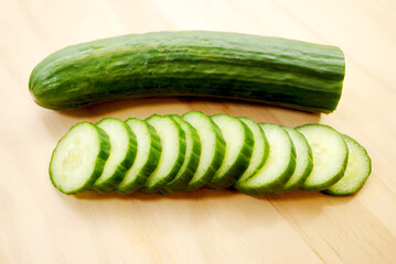 Whole and Sliced Cucumbers on a Wooden Cutting Board