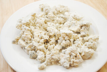 Moldy Crumbled Blue Cheese on a White Plate