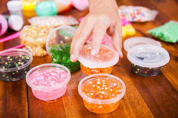 Young kids playing with colorful slime kit with glitter, toys, texture craft balls, and sparkles