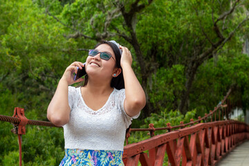 Una joven atractiva asombrada responde una llamada al aire libre, verde,naturaleza,arboles,bosque,celular,